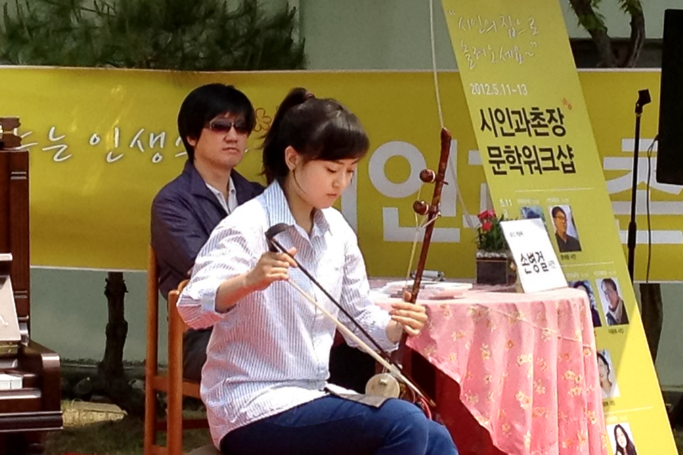 사진1. 야외 정원에서 강연을 위한 테이블 앞에 필자가 앉아 바로 앞에서 공연하는 해금연주자의 연주를 듣고 있다.