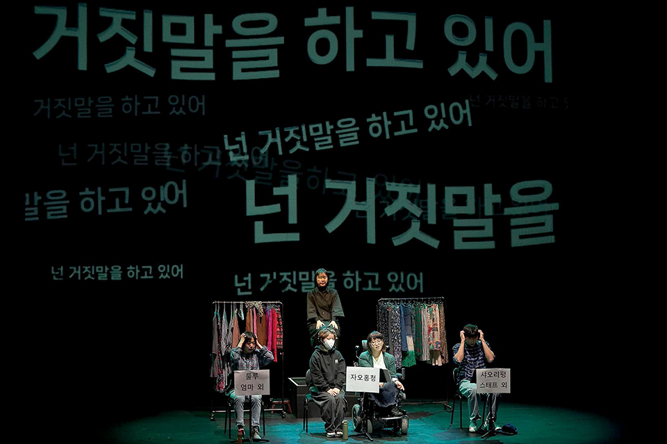 세 배우 앞 보면대에는 ‘룰루 엄마 외’, ‘자오홍청’, ‘샤오리펑 스태프 외’라고 역할이 쓰여있다. 자오홍청 자리에는 배우와 활동지원사가 앉아 있다. 뒤에 수어통역사가 있다. 무대 배경에는 ‘넌 거짓말을 하고 있어’라는 문장이 크고 작게 떠다니고 있다.