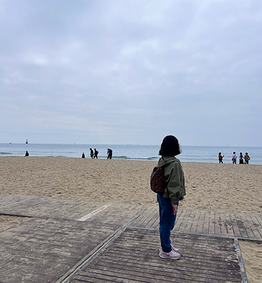 수평선이 보이는 해변 진입로에 깔려 있는 경사로에 서서 바다를 바라보고 있는 필자