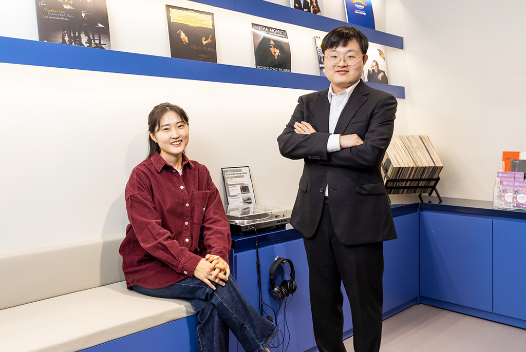 LP 플레이어와 헤드폰, LP 음반 등으로 장식된 실내 공간에서, 신찬미 감독은 캐주얼한 복장으로 수납의자에 앉아 있고, 옆에 검정색 수트를 입은 방찬우 성악가가 팔짱을 끼고 서 있다.