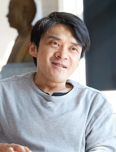 회색 옷을 입은 김원영이 얼굴에 미소를 띄며 이야기하고 있다.