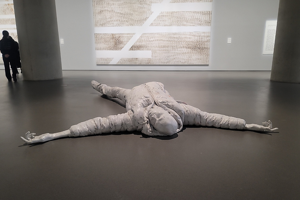 전시장 한가운데 바닥에 사람 형상의 거대한 흰색 조형물이 팔다리를 벌린 채 위를 향해 누워있다. 파마용 엔드페이퍼를 주재료로 사용한 대형 혼합매체 작품이다. 뒤편 벽에는 대형 회화 작품이 걸려 있다. 