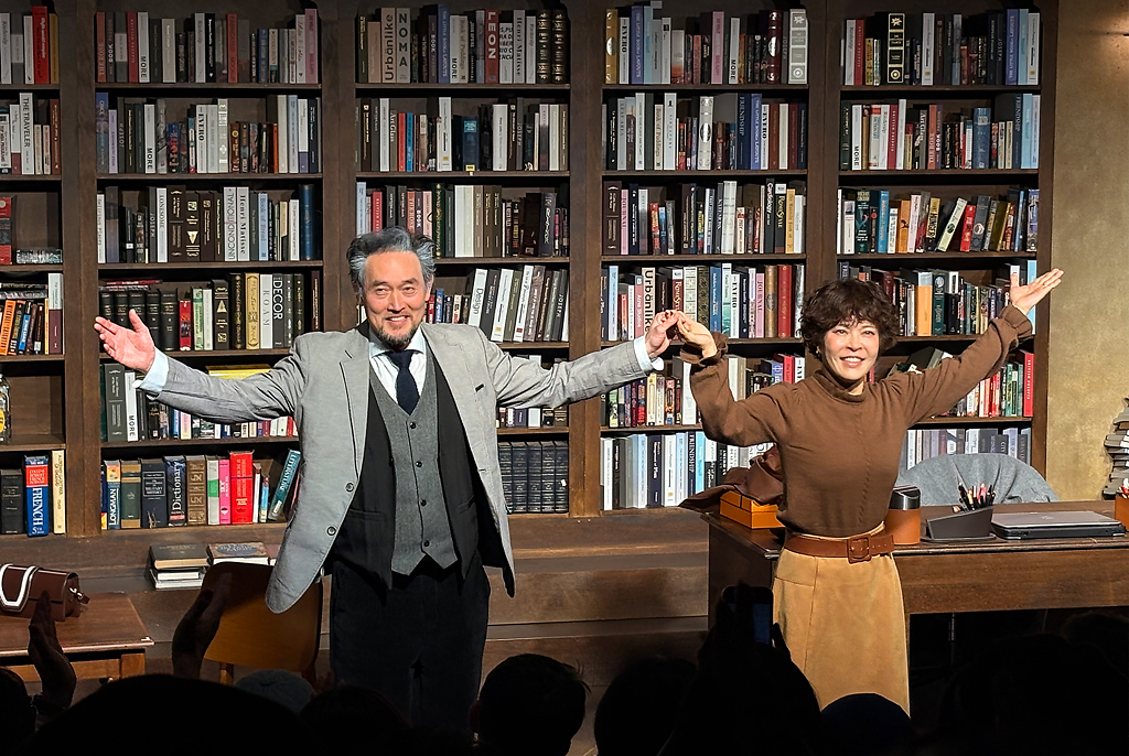 서재처럼 보이는 무대 세트 앞에서 프랭크 역 김명수 배우와 리타 역 조혜련 배우가 관객을 향해 손을 맞잡고 인사하고 있다.