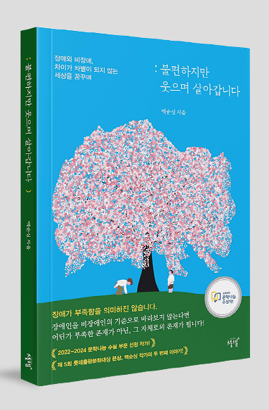 하늘색 배경 으로 분홍색 꽃이 가득 핀 큰 나무가 초록색 언덕 위에 있고, 그 나무 아래에 두 사람이 서 있는 그림의 책표지. ‘불편하지만 웃으며 살아갑니다’, ‘백순심’이라고 쓰여 있다.