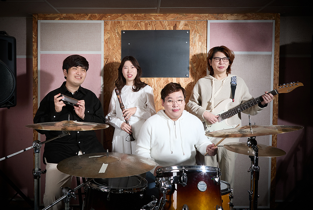 앞줄 중앙에는 흰색 후드티를 입은 박호진이 드럼 세트 뒤에 앉아 있고, 그 뒤로 세 명의 멤버가 서 있다. 왼쪽부터 검은색 셔츠를 입은 이인혁이 하모니카를, 흰색 원피스 입은 서지은이 리코더를, 아이보리색 후드티를 입은 우병욱이 일렉기타를 들고 있다.