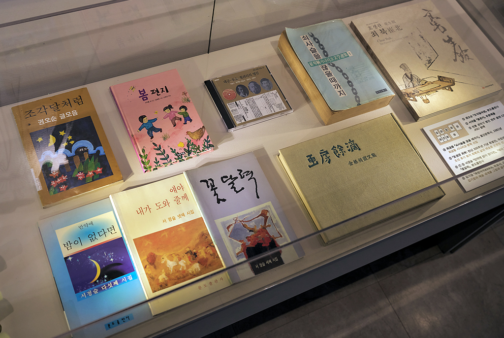 유리 전시 케이스 안에 한국 장애 예술인들의 도서와 음반 자료들이 진열되어 있다. 권오순의 시집 『조각달처럼』, 서덕출의 동시집 『봄편지』, 서정슬의 시집 여러 권, 음악 CD, 한문으로 쓰인 문집 등이 포함되어 있으며, 오른쪽에는 각 자료에 대한 설명 안내판이 부착되어 있다.