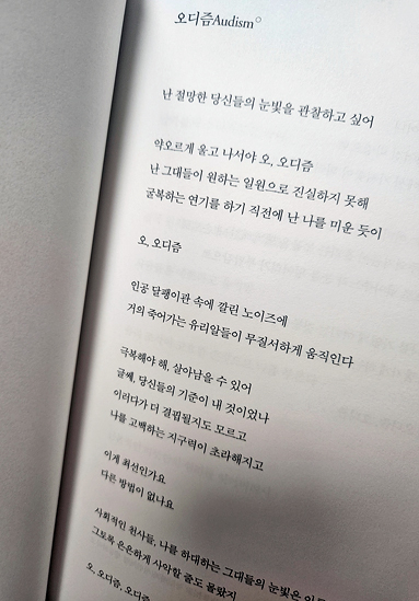 양쪽으로 펼쳐진 책의 오른쪽 면에 시가 적혀 있다. 오디즘(Audism) 난 절망한 당신들의 눈빛을 관찰하고 싶어 // 약오르게 울고 나서야 오, 오디즘 / 난 그대들이 원하는 일원으로 진실하지 못해 / 굴복하는 연기를 하기 직전에 난 나를 미운 듯이 // 오, 오디즘 (이하 생략) 