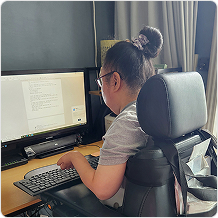 책상 앞 의자에 앉아 모니터를 보며 키보드를 치고 있는 여성의 뒷모습