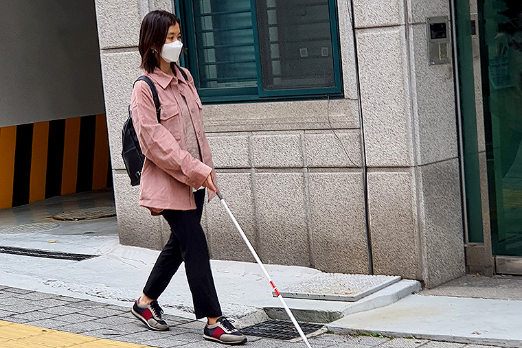 필자가 흰지팡이를 사용하여 보행하고 있다. 