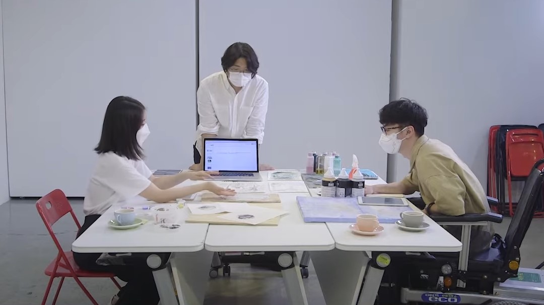 팀 D(디) 김환, 최일준, 김하경 작가 세명의 시각예술가가 테이블에 모여 회의를 하고 있다.